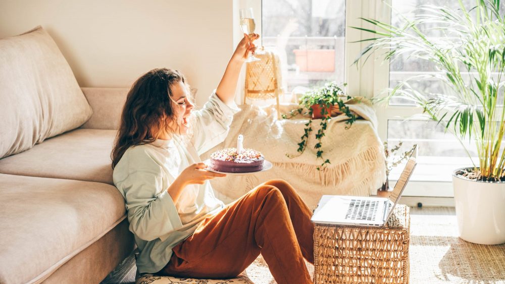 Woman celebrating a virtual birthday with wine and cake