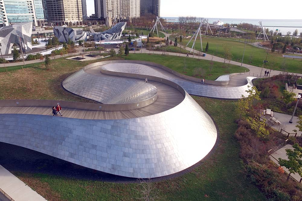 View of a curved walking structure surrounded by green grass at Maggie Daley Park, a free thing to do in Chicago.