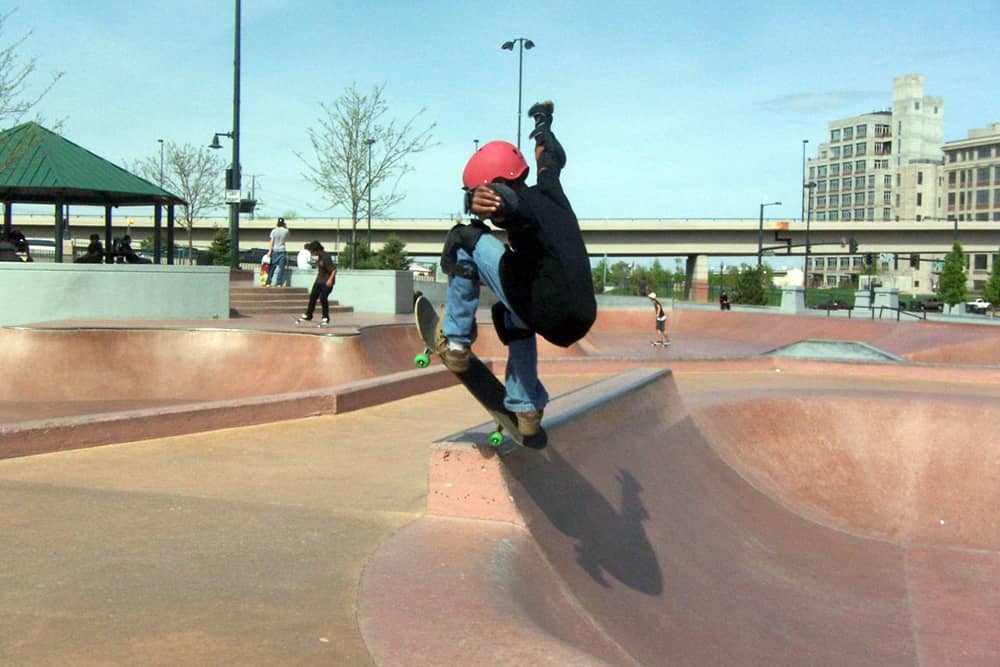 A young boy pulls a trick on his skateboard at the Denver Skatepark, one of the best free things to do in Denver.