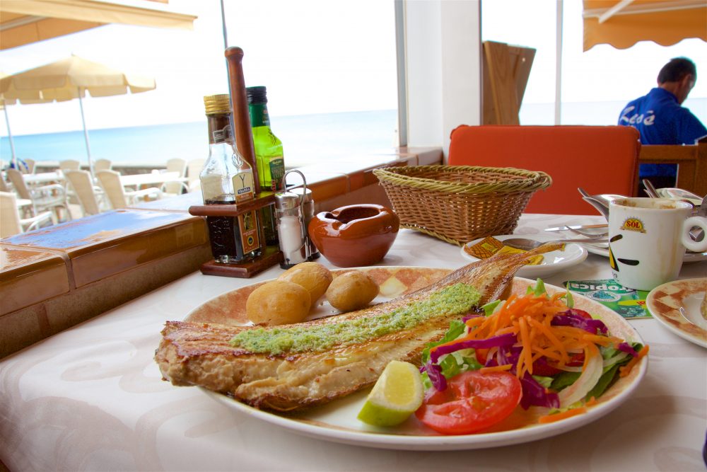 Fresh fish with a green sauce and vegetables at a restaurant in Morro Jable with a water view