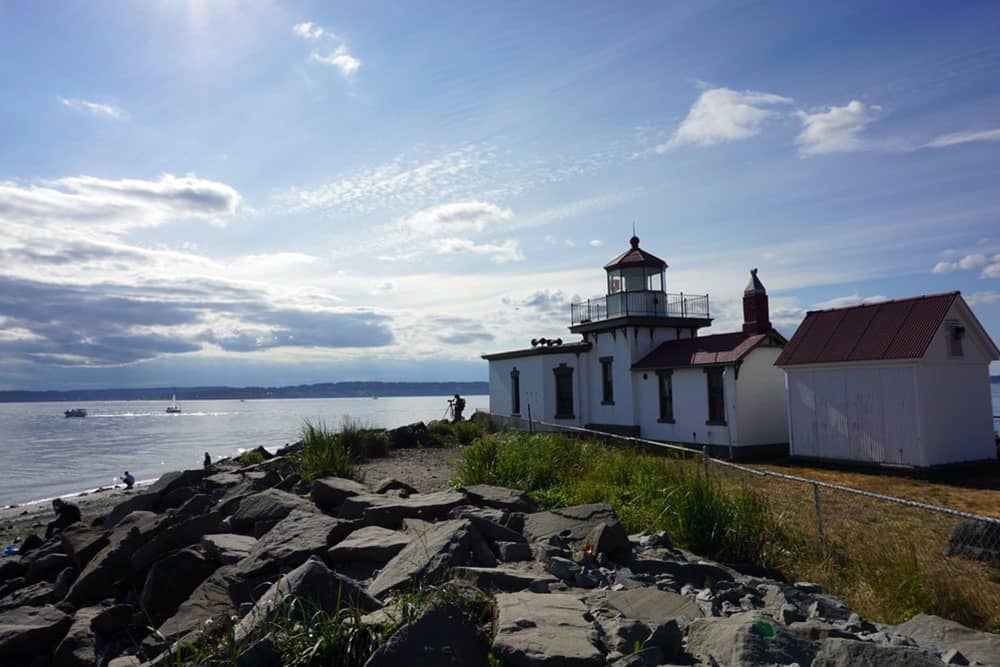 Historic white West Point Lighthouse on the coast at Discovery Park, a free and romantic cheap date idea in Seattle