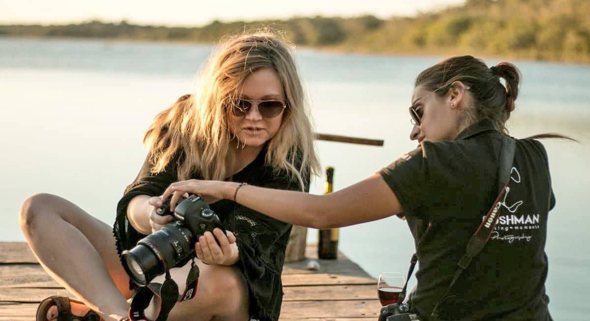 A photography tour guide showing a guest how to change the settings on her large camera