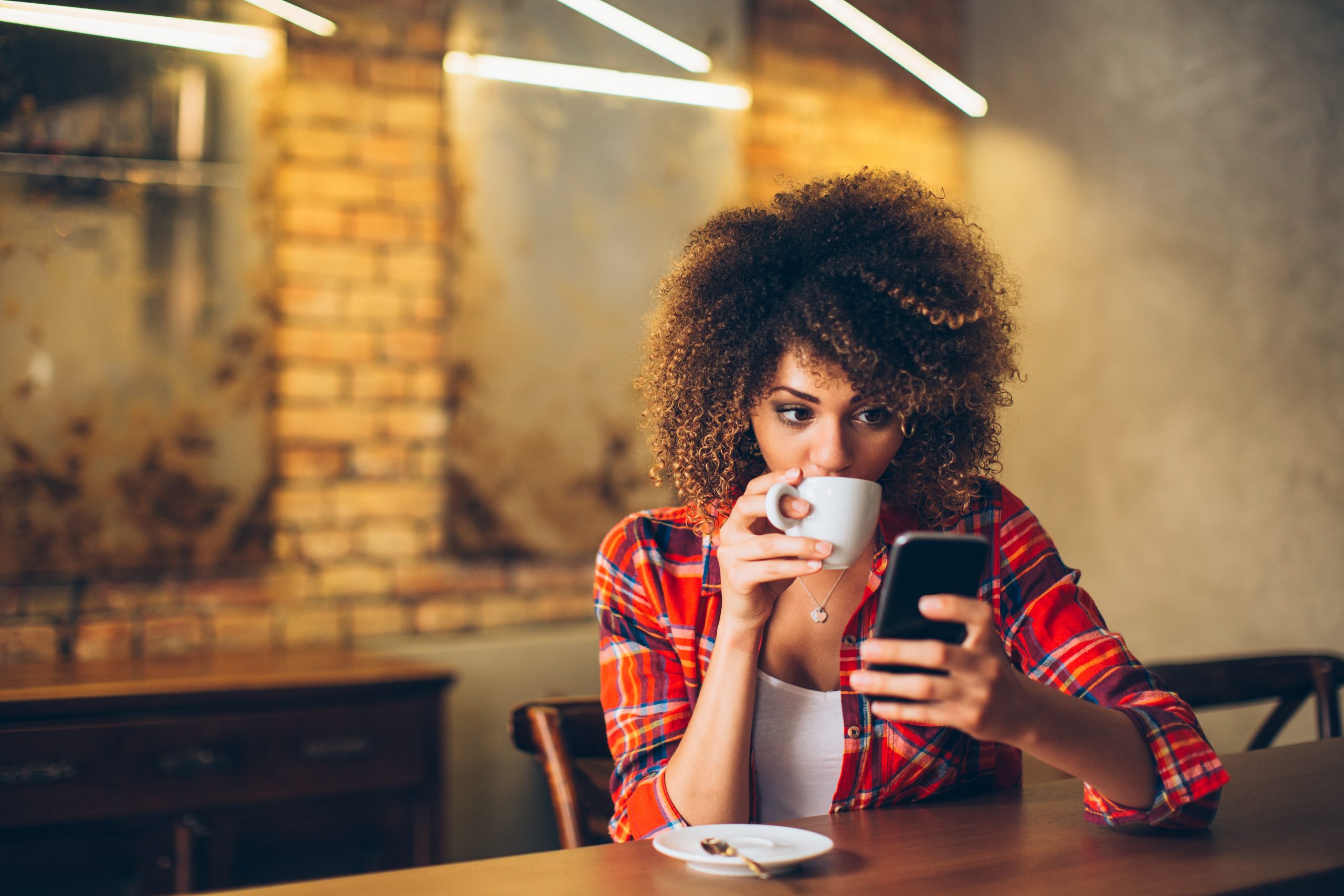 Black woman at a café on her phone
