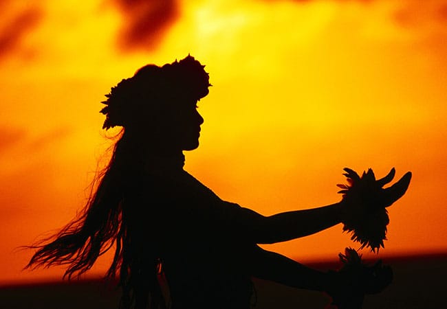 Silhouette of performer as sun sets at luau in Honolulu