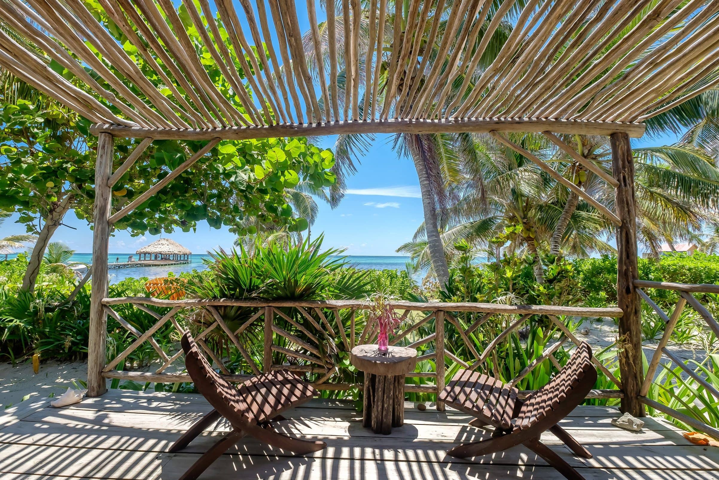 The outdoor deck with colorful jungle surroundings and table and chairs to relax and lounge by the ocean at an AkBol Yoga Retreat in Belize