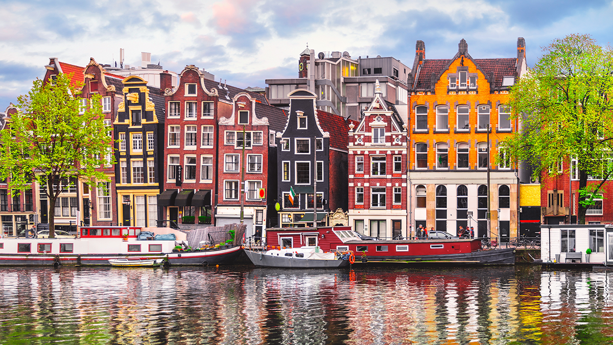 Colorful houses reflect off the water in Amsterdam