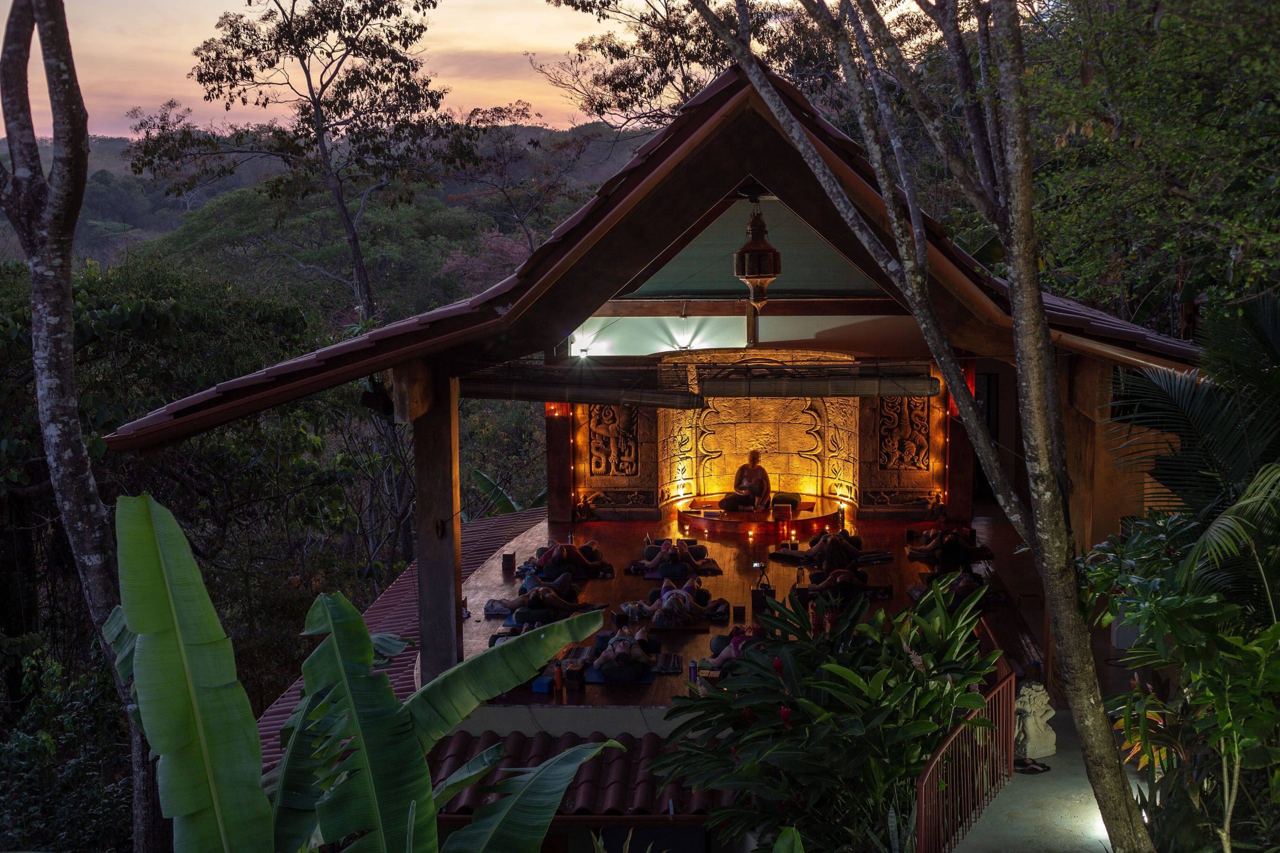 A sunset scene at the Anamaya Yoga Retreat in Costa Rica with a candlelit meditation hut.