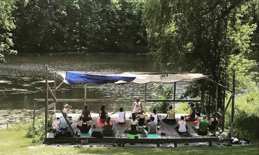 A yoga class held lakeside surrounded by nature at the Ananda Ashram Monroe yoga retreat in New York.