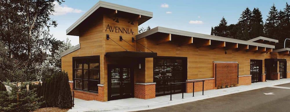 The entrance to the Avennia Winery in Seattle, Washington features a brown wooden building.