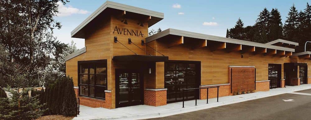 The entrance to the Avennia Winery in Seattle, Washington features a brown wooden building. 