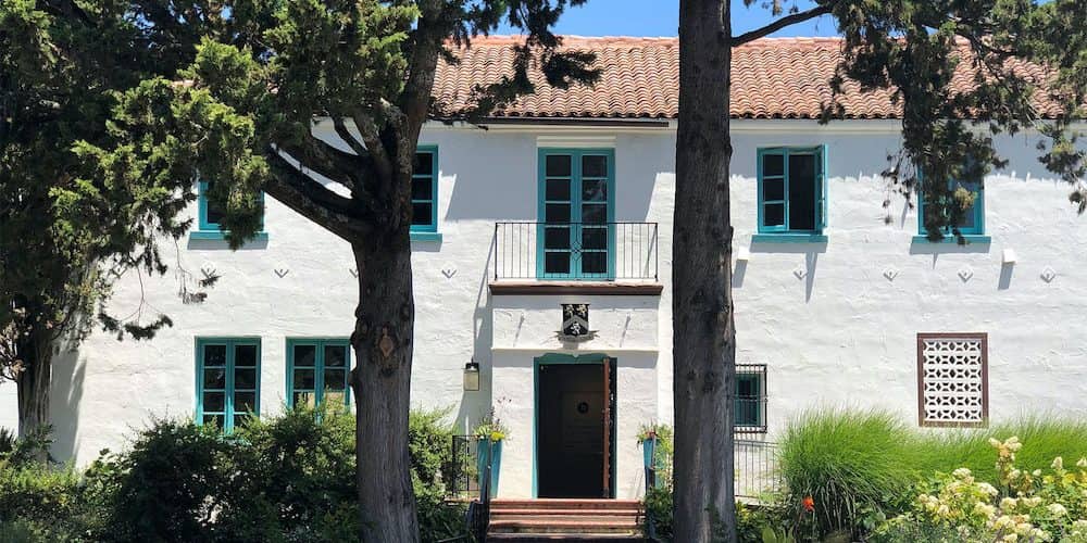 A beautiful white building with blue windows and red roof welcomes visitors to Bartholomew Winery in Seattle, Washington, with their tasting rooms and excellent wines. 