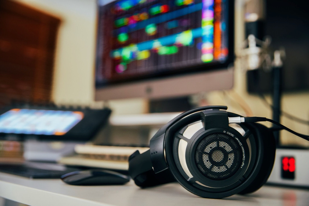 Earphones lay in front of a computer showing composition software