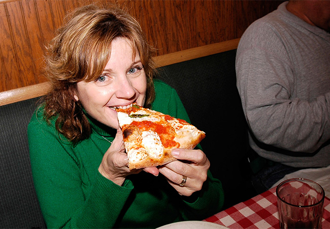 Woman eating a slice of pizza in New York