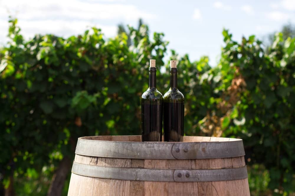 Two bottles sitting on a wine barrel in the carlton yamhill wine region of oregon. 