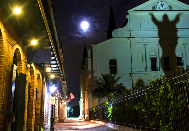 Cemetery at night with Statues silhouetted on wall