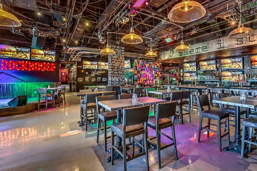 The brightly colored entrance and bar of Rockhouse Las Vegas, serving cheap food and drinks with walls covered in TVs and neon lights