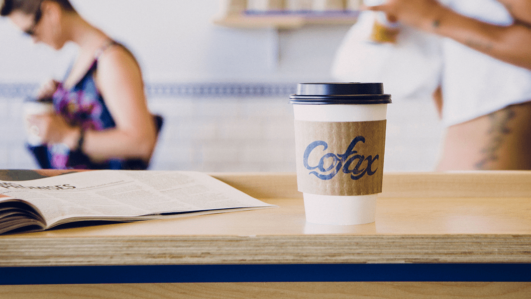  A branded cup of Cofax coffee sitting on a wooden table at the popular coffee house offering cheap deals in Los Angeles, California.