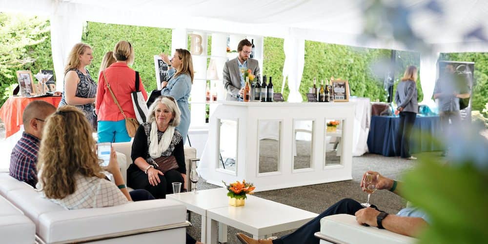 A group of people enjoy an outdoor wine tasting environment at the beautiful Columbia Winery of Woodinville, Washington.