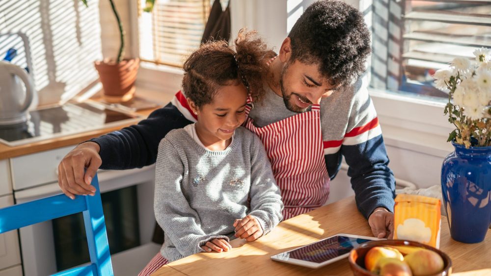 Father and daughter taking an online cooking class together