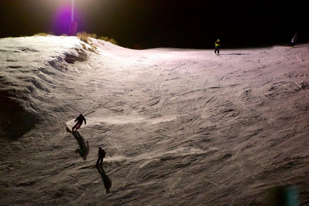 Skiers on a slope at night