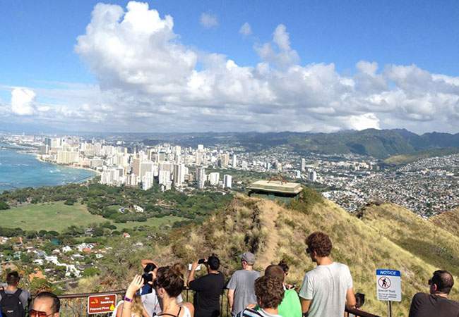 Large hiking group takes pictures of city from trail overview in Honolulu