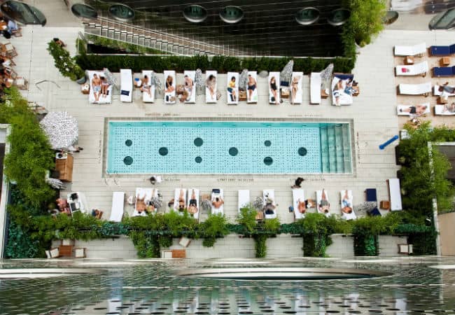 New York City’s Dream Downtown’s glass-bottom pool with patrons lounging poolside.