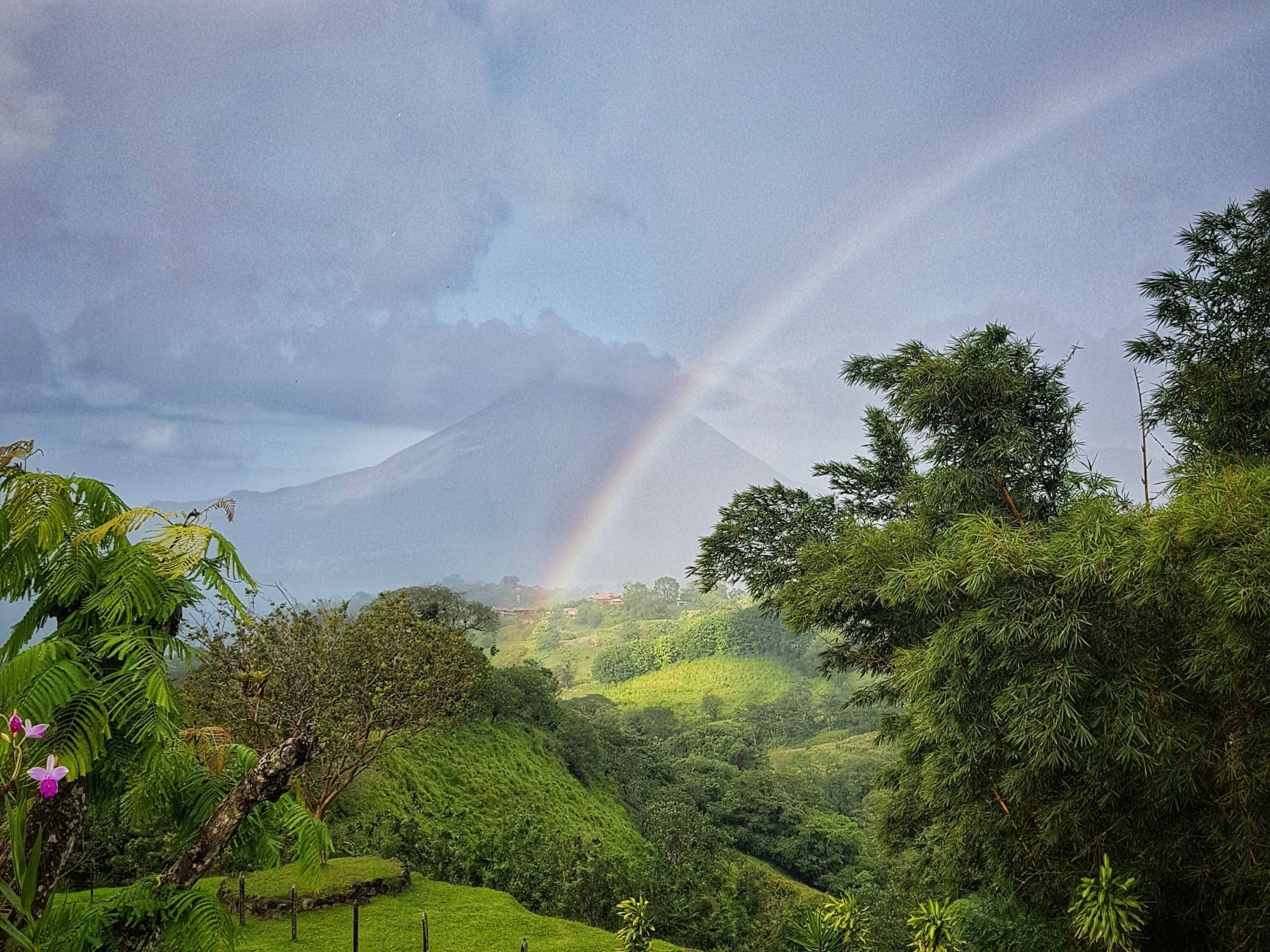 A beautiful rainbow scene from the retreat at Essence Arenal in Costa Rica overlooking the lush green jungle canopy.