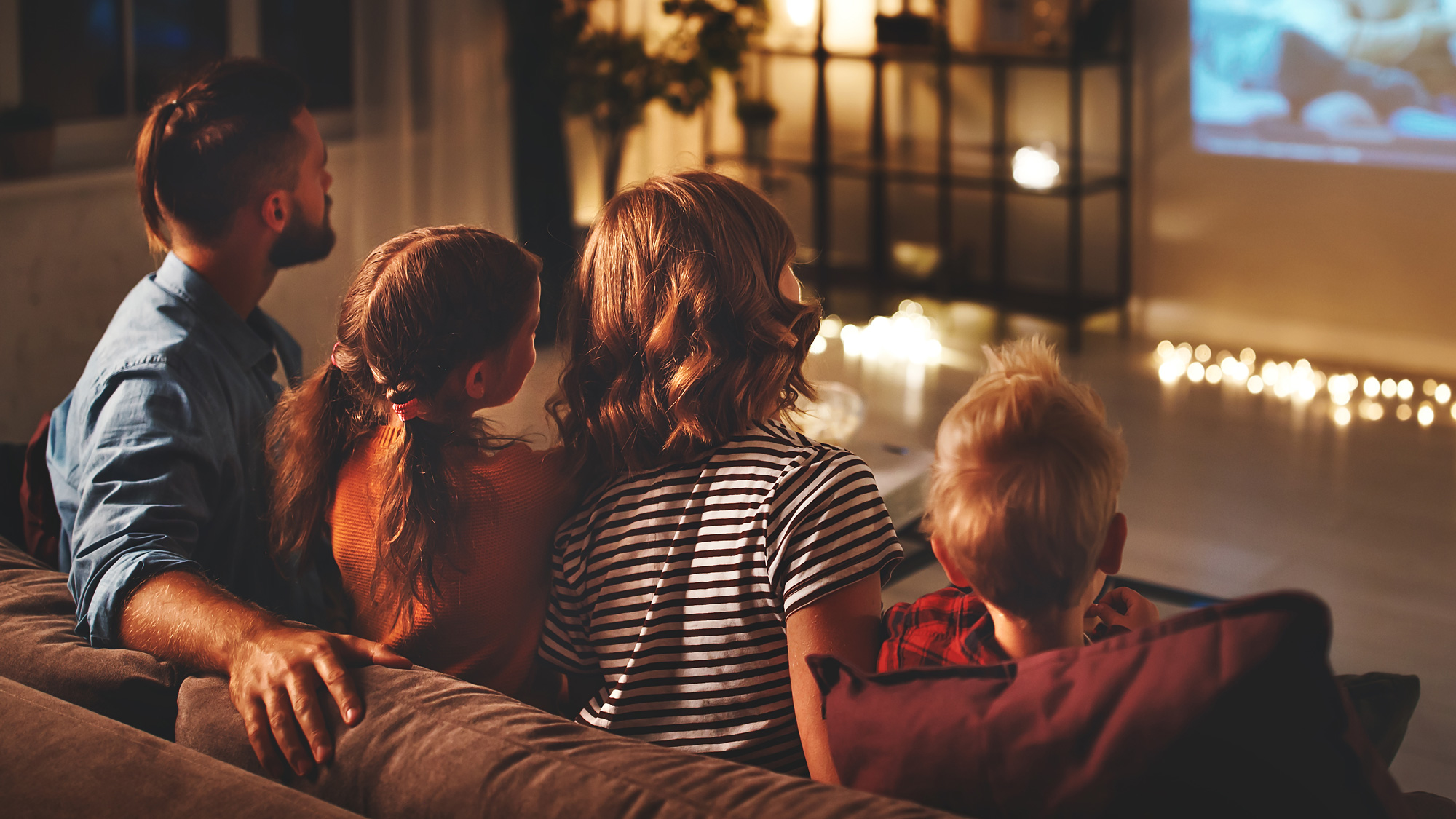 Young family sitting on a couch and watching a movie together