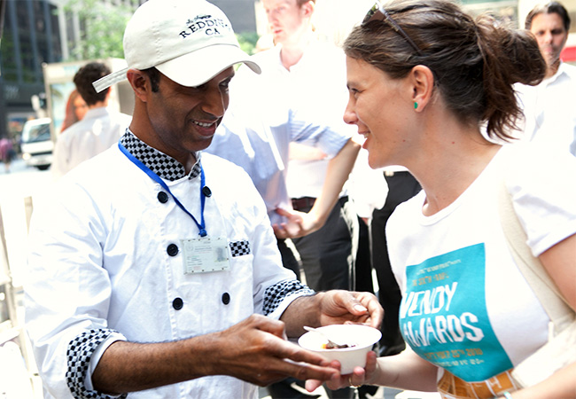 Food being exchanged by cart patron and cook in Midtown