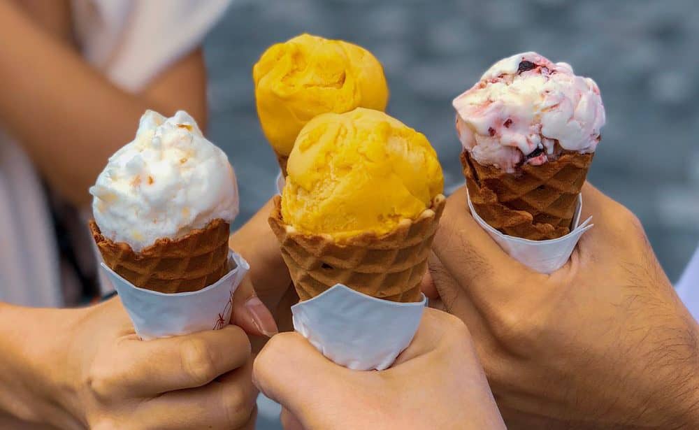 Four people holding out cones of ice cream
