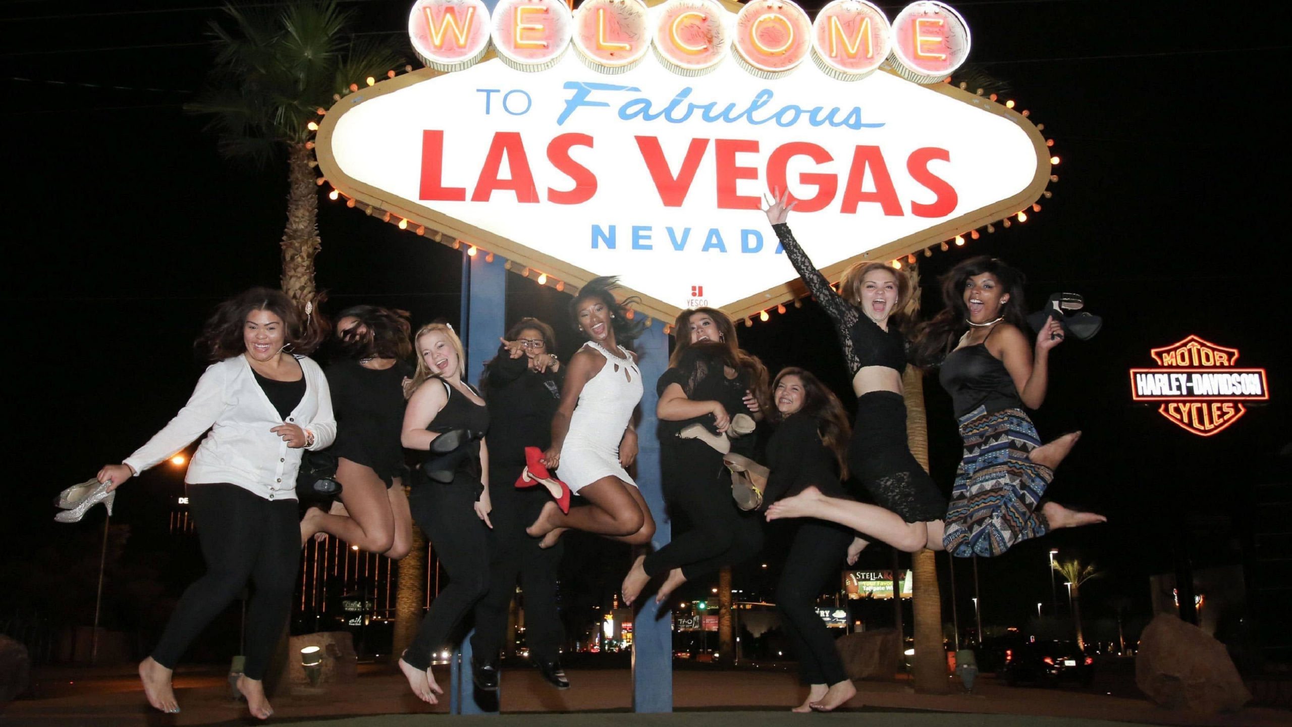 A group of friends jumping in front of the Welcome to Las Vegas sign at night