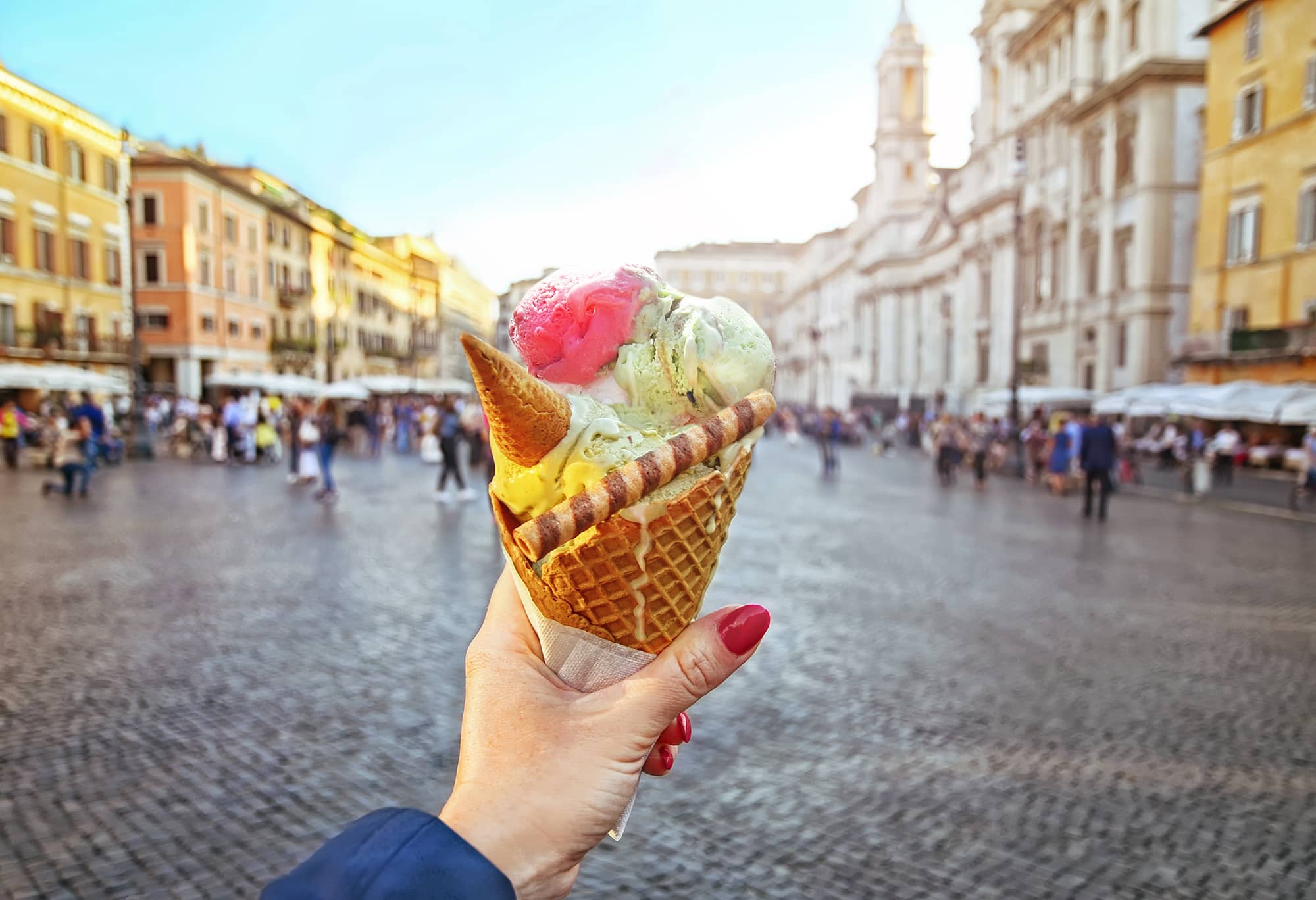 A woman holding up a huge cone of gelato in Italy