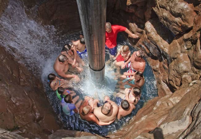 Patrons playing in the Wailea Canyon Activity Pool as water cascades from above.