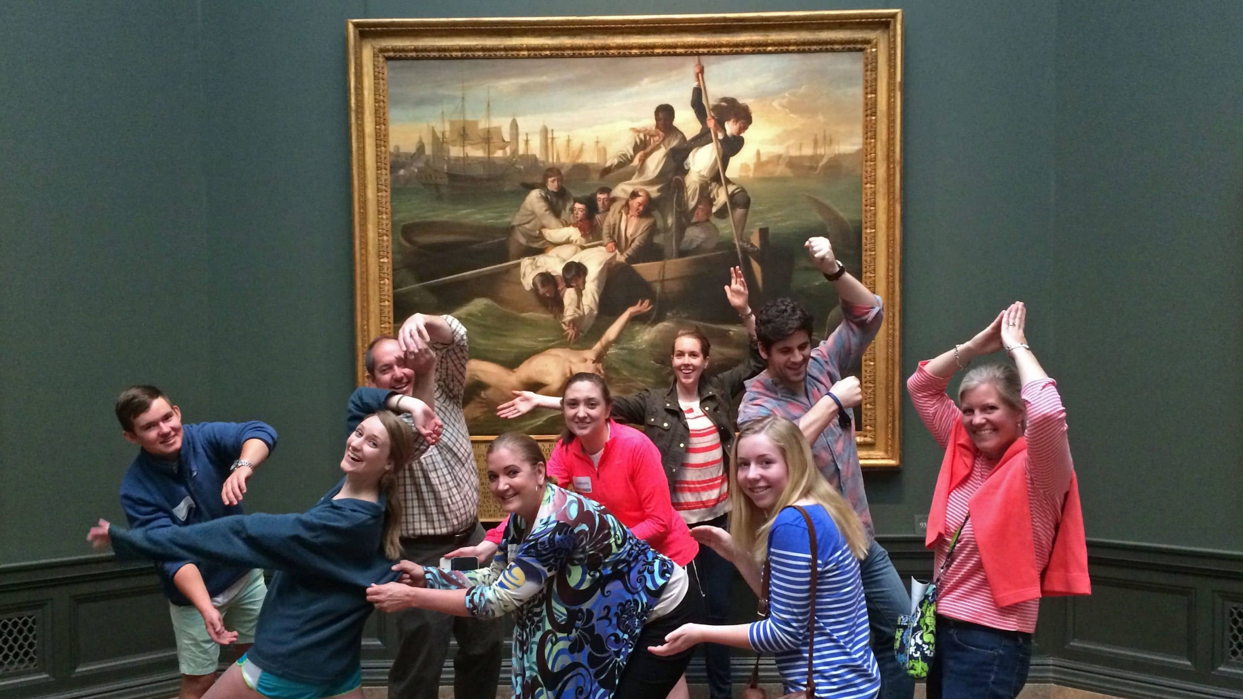 Group of people recreating a large painting in a museum behind them