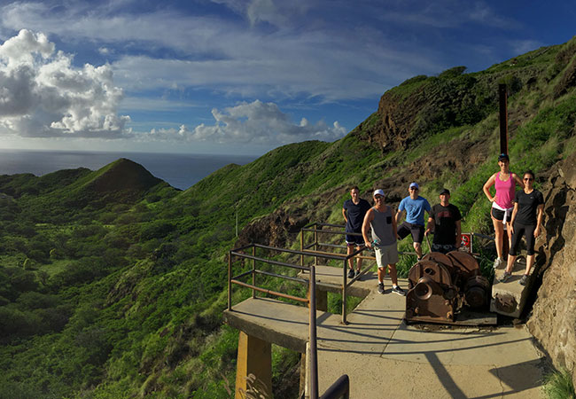 Group stands on concreate platform with mountain range in background in Honolulu