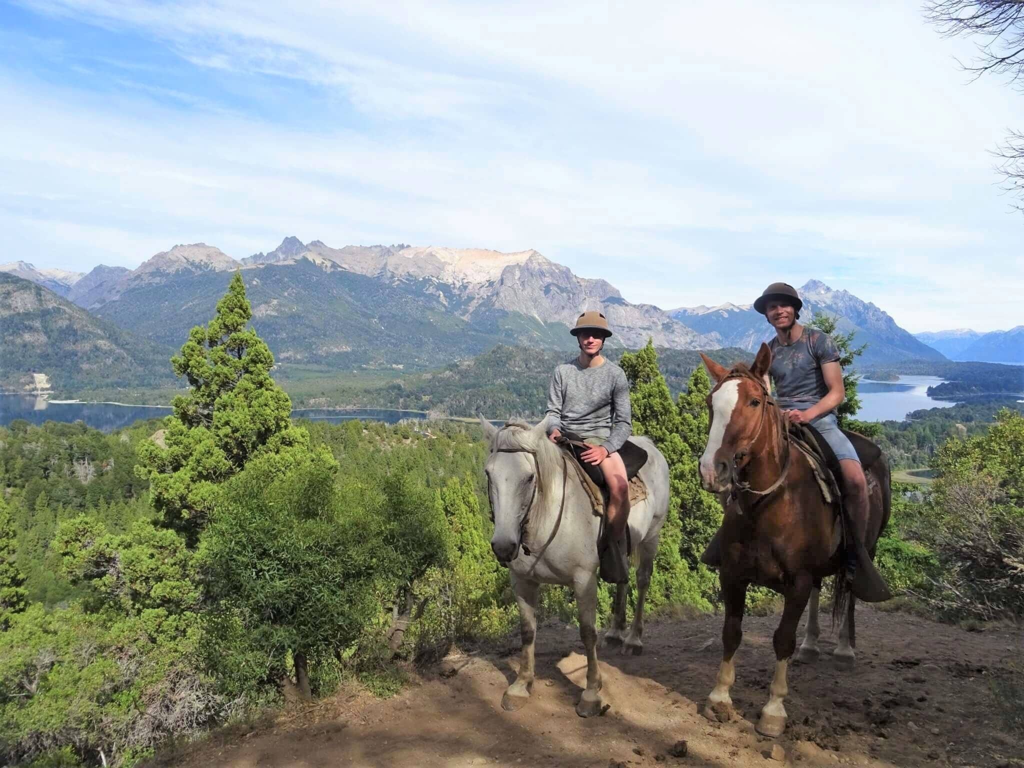 Horseback Riding in Patagoina with mountains and a river in the background