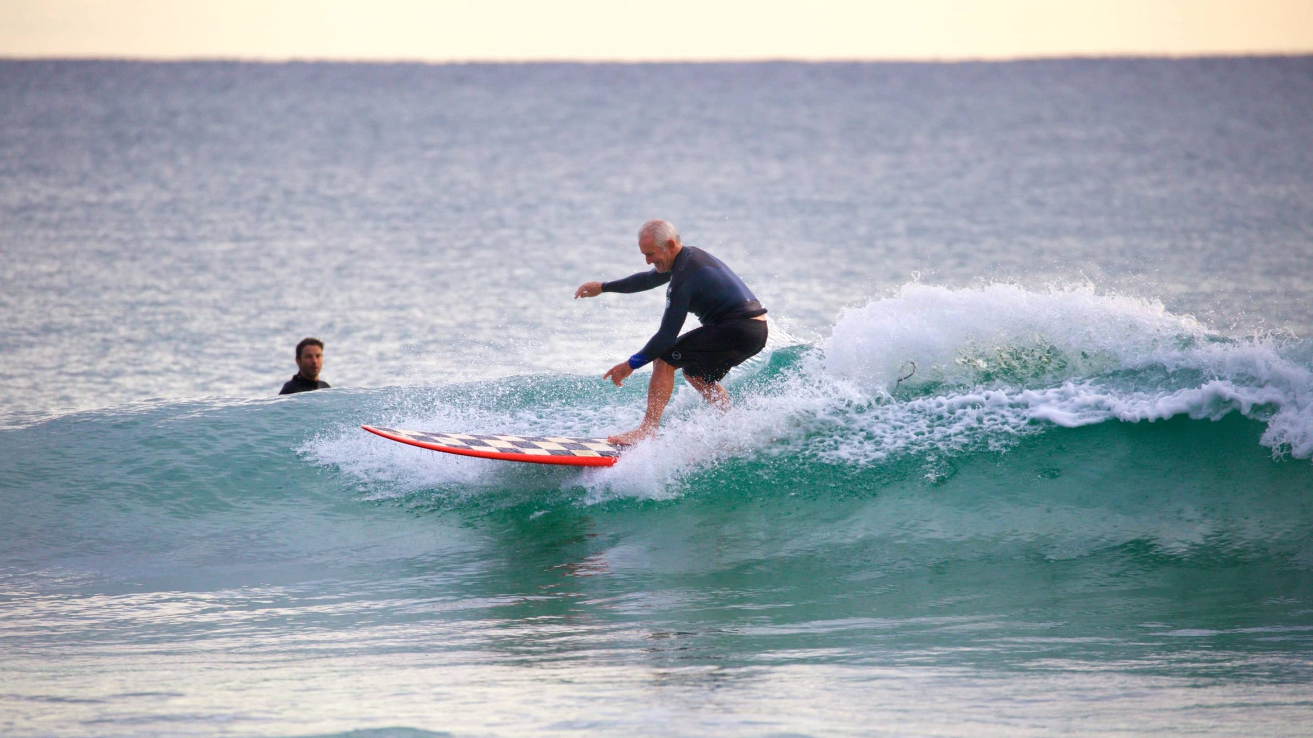 A male surfer rides the top of a wave at the beach at Snapper Rocks