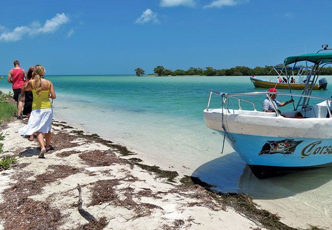 People walking down beach from boat on Isla Holbox in Cancun