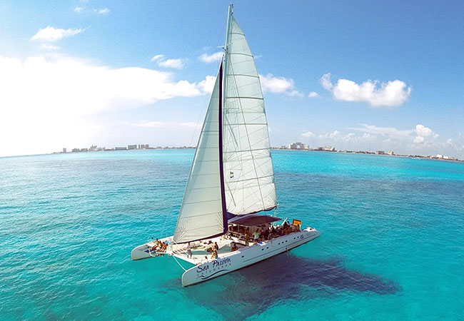 Catamaran at full sail in clear blue waters of Cancun