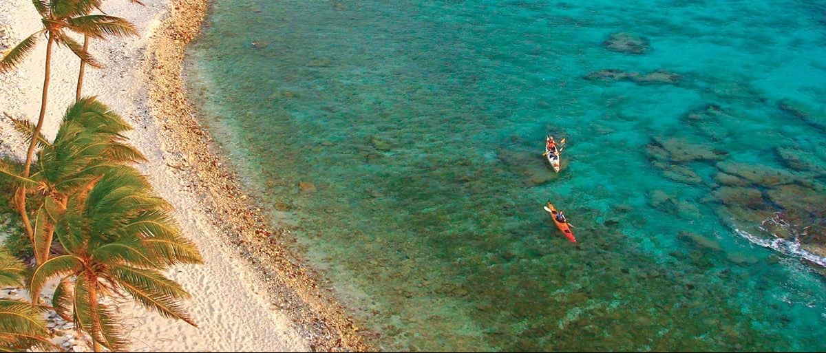 People kayaking in crystal clear water at a retreat held by Island Expedition Belize Adventure Basecamps, Glover’s Reef and Lighthouse Reef in Belize.