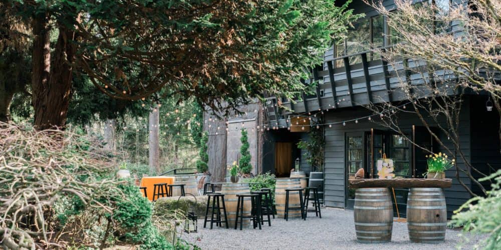 JM Cellars has the most beautiful cabin in a lush forest area and the outdoor patio shows wine barrels as tables and lots of rustic decor to create a warm, romantic environment for wine-tasting.