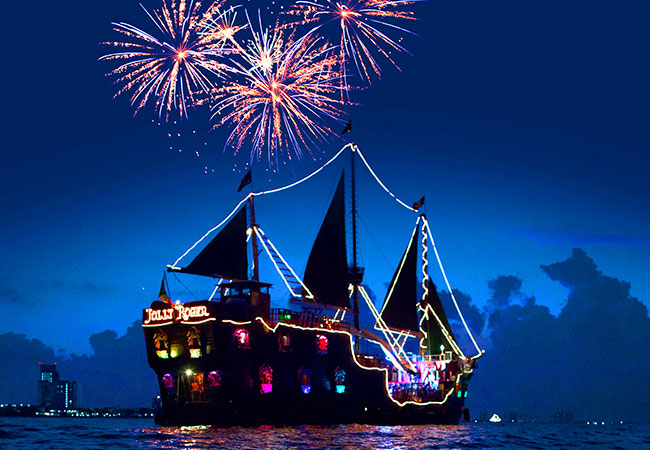 Jolly Roger pirate ship lit up while launching fireworks at night in Cancun