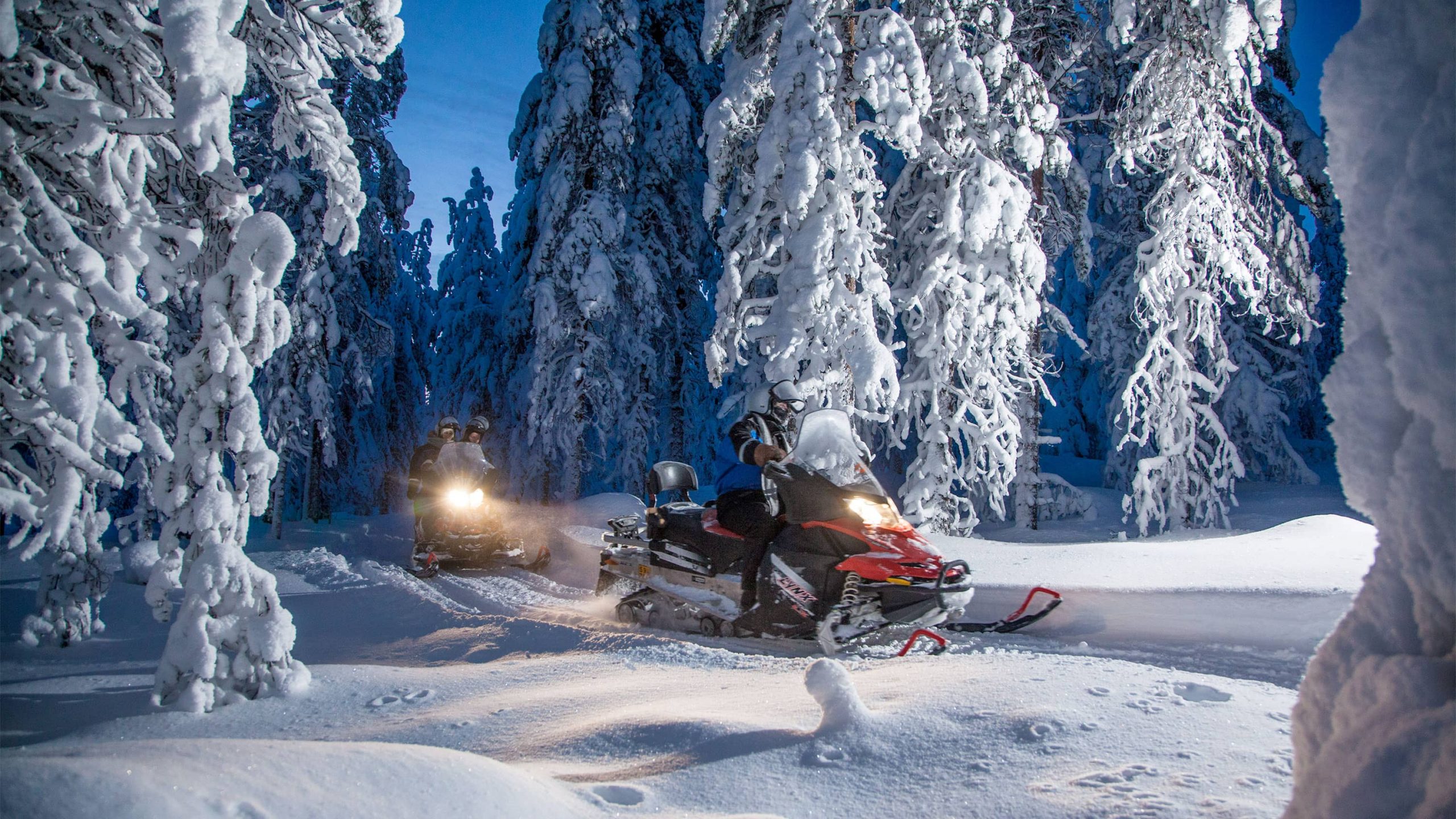 People head to a campfire on a snowmobile.