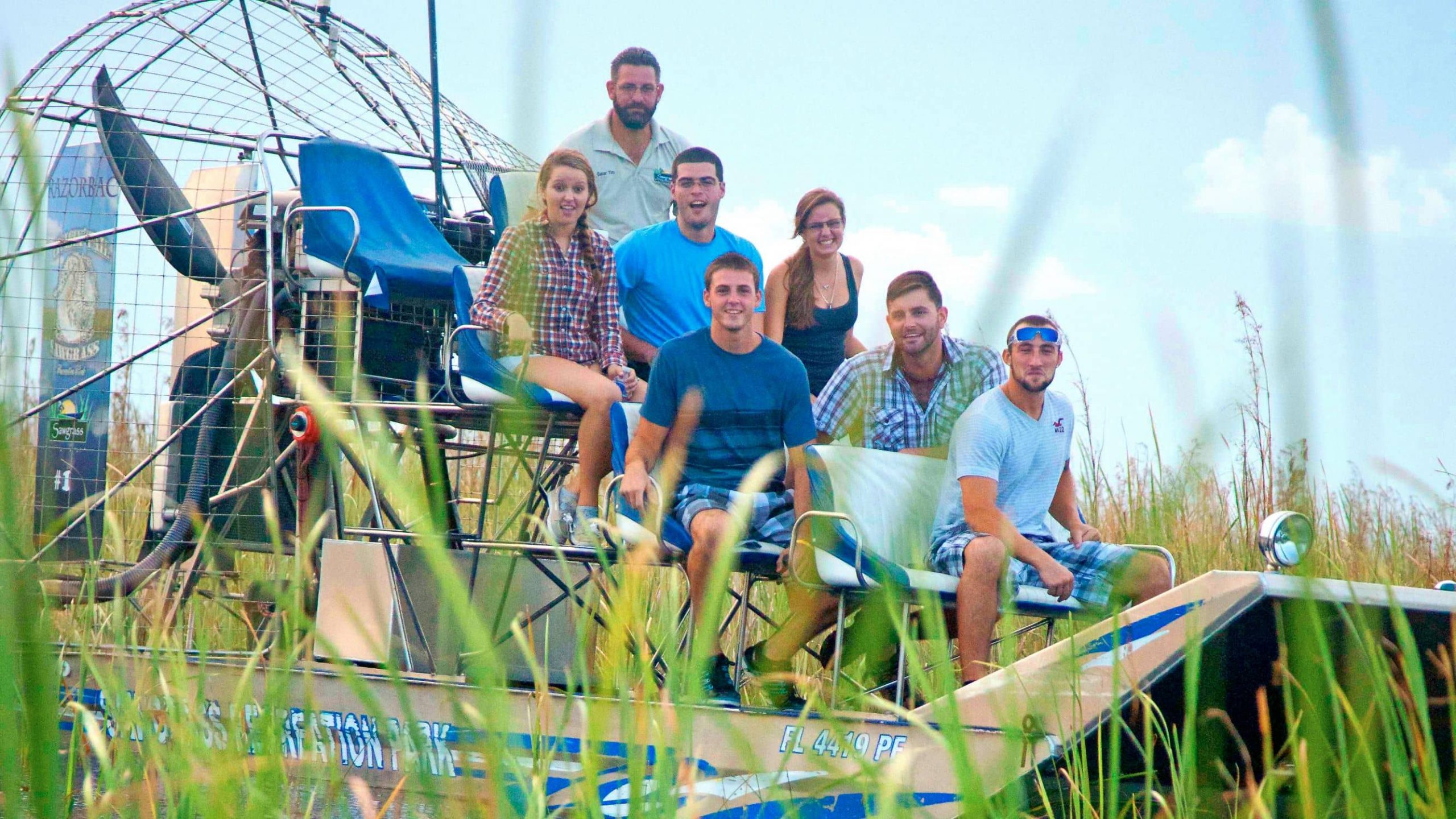 A group of friends sit on an airboat in the Everglades.
