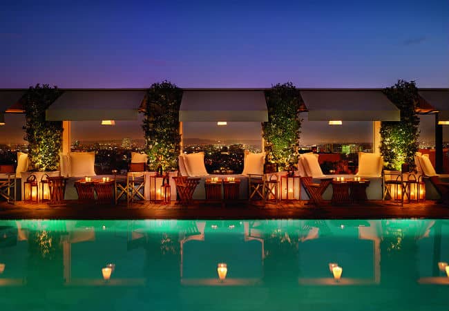 Emerald colored pool at night with daybeds lining the water at the Mondrain in Los Angeles, California.