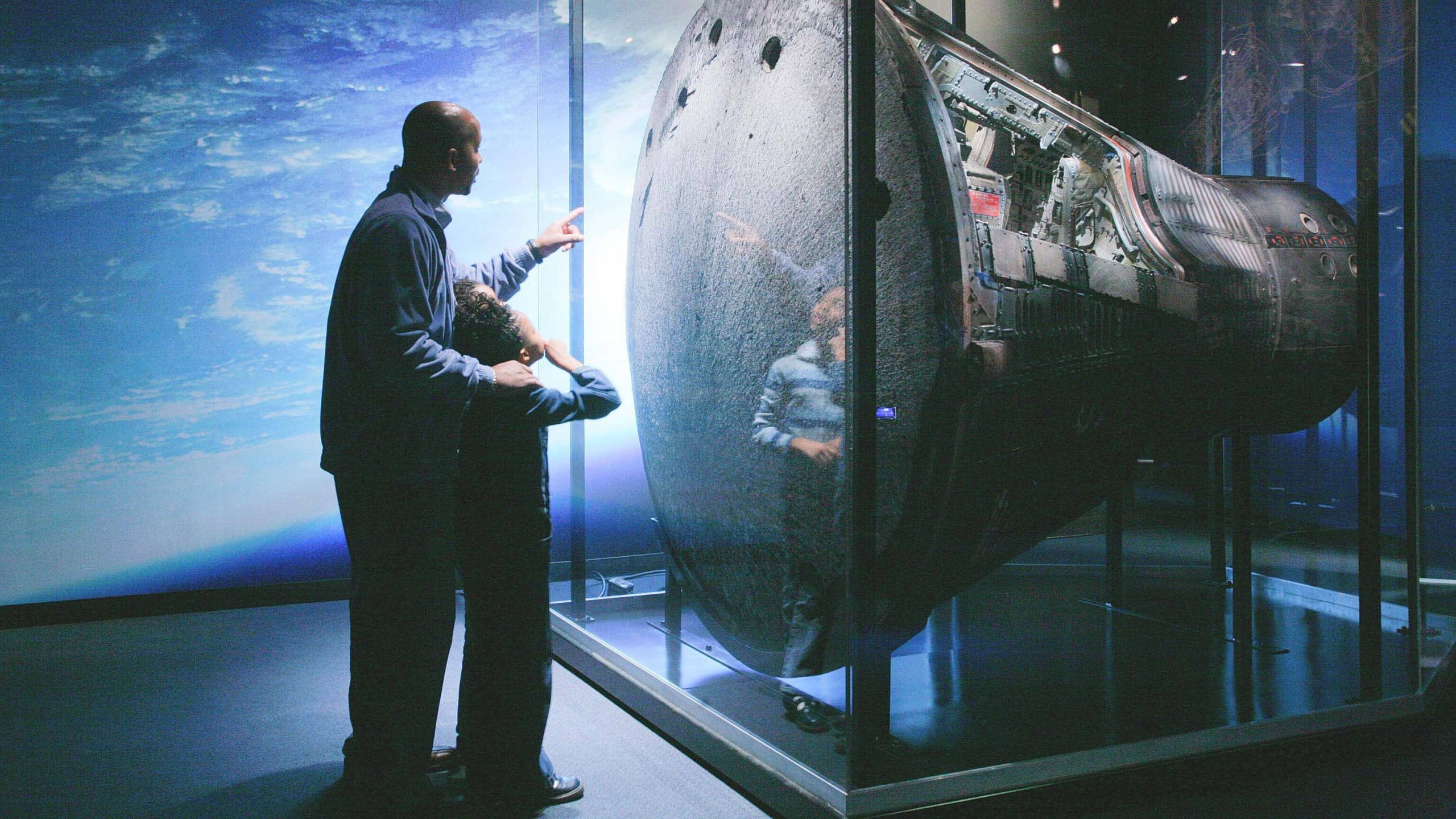 A father and son explore a museum exhibit.