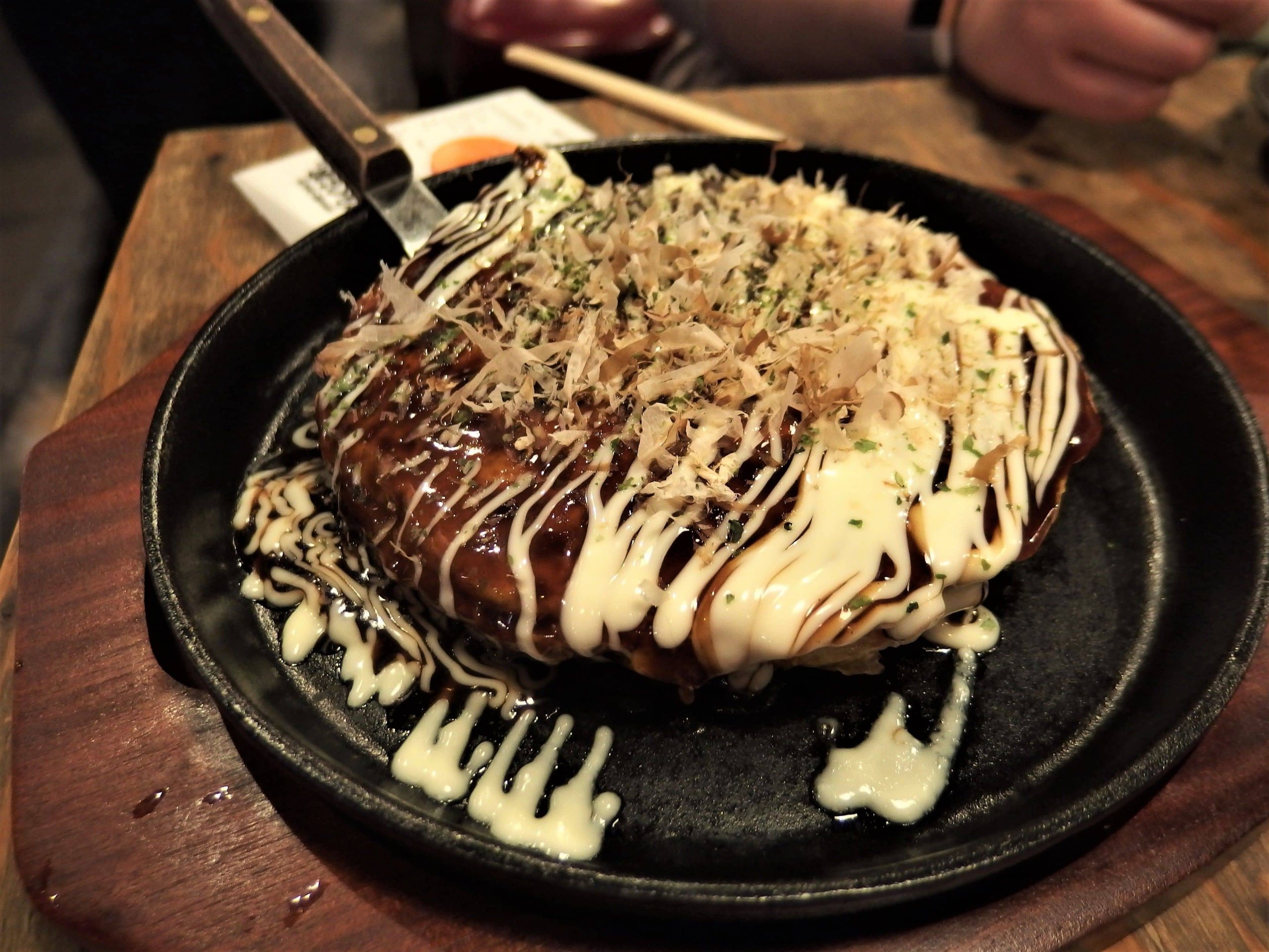 Okonomiyaki served in a pan and covered in mayo and bonito flakes in Osaka