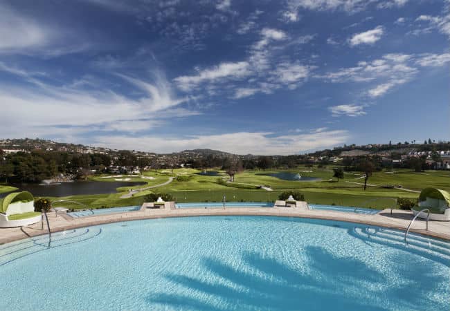 Large rounded pool overlooking the golf course and blue skies at the Omni La Costa Resort and Spa in Carlsbad, California.