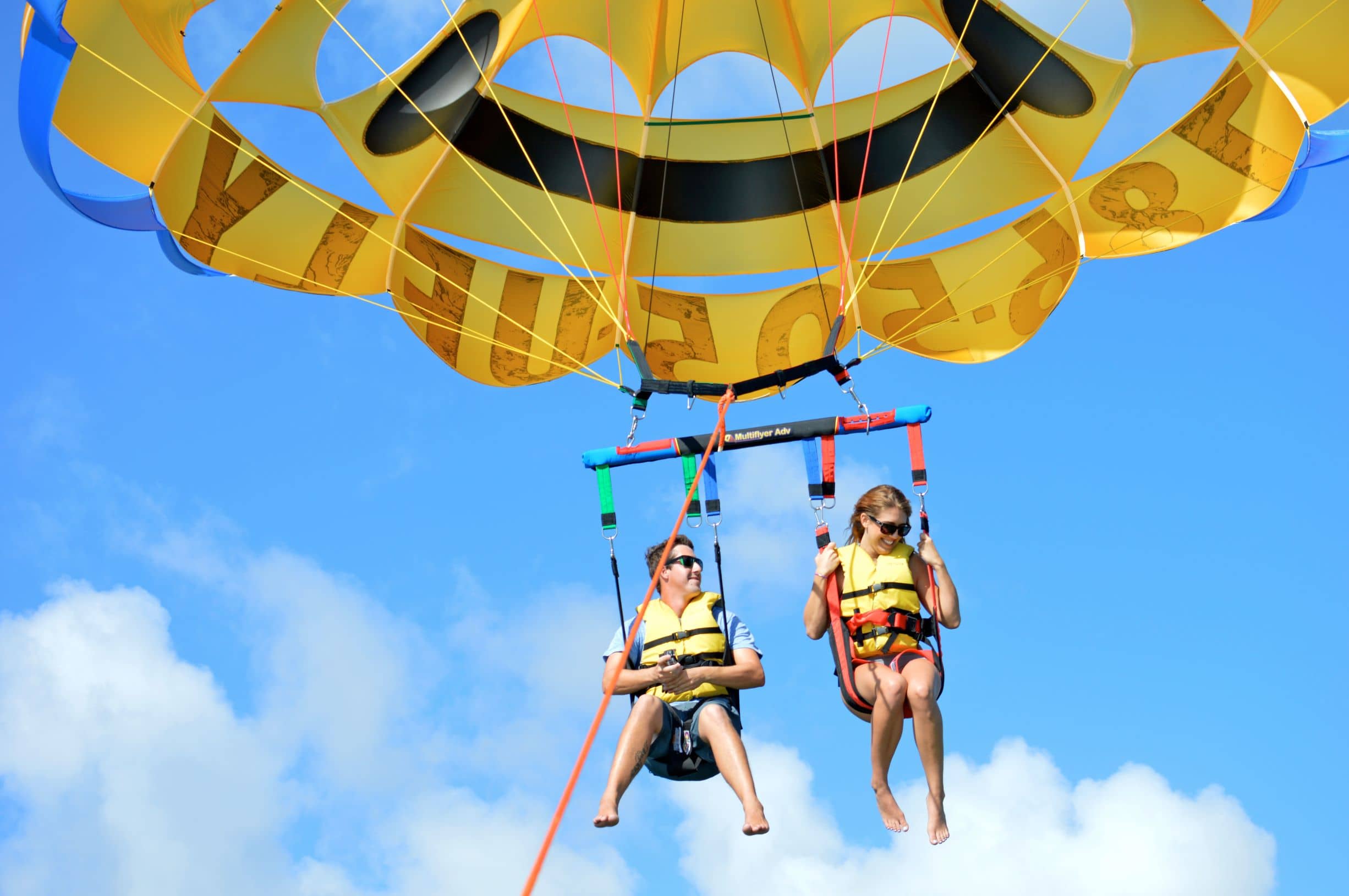 Two parasailers sail through the sky.