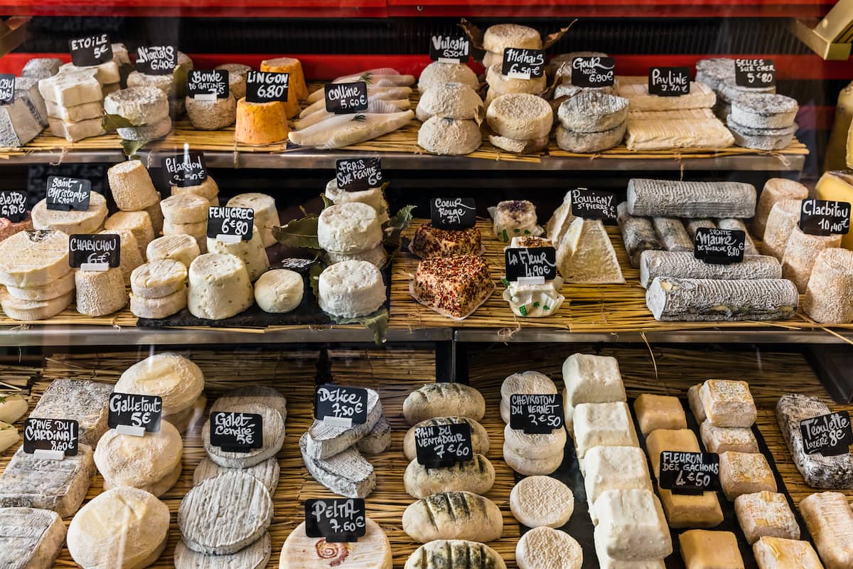 A large selection of different french and italian cheeses on the counter of a small store at the Aligre Market (Marche d'Aligre) in the Bastille district.